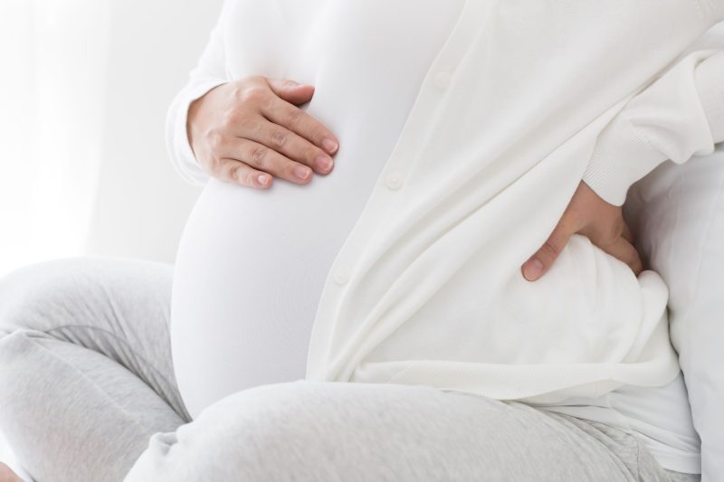 prenatal chiropractic care helping pregnant woman in white clothing