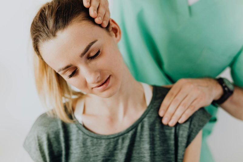 Chiropractor adjusting neck of a woman with migraine pain in Frankfort clinic